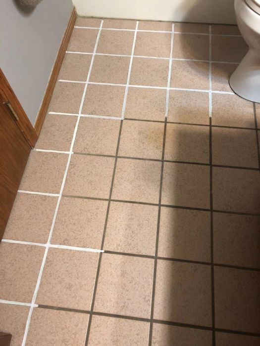 A bathroom floor with white grout applied from the pen and brown grout in areas that haven't been touched up yet.