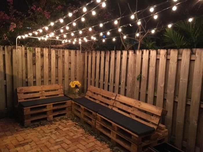 reviewer's photo of lights strung above a patio area with benches underneath