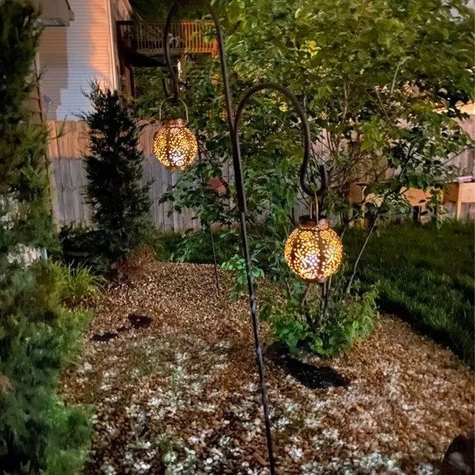 A reviewer-submitted image showcasing two solar lanterns beautifully suspended in a yard, radiating a soft, inviting glow.