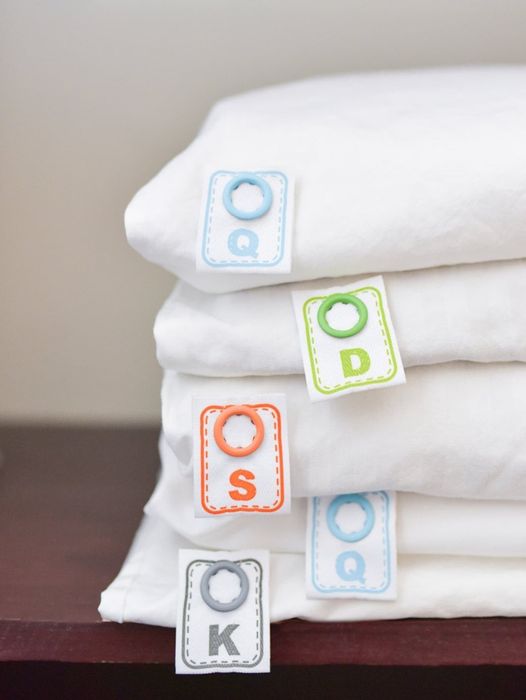 A light blue label for queen, a light green one for double, an orange for single, and a gray one for king-sized sheets.