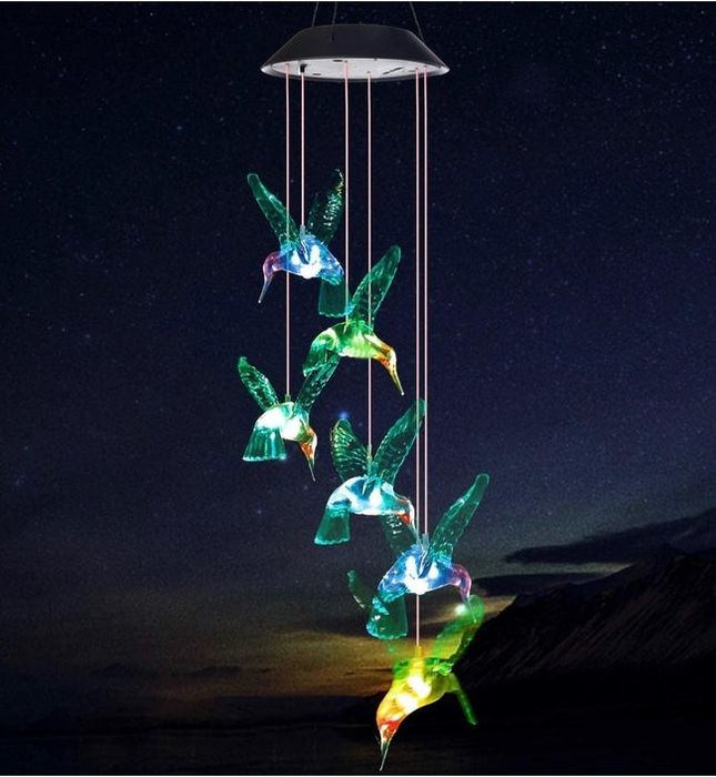 The hummingbird wind chimes glowing against a dark, starry sky