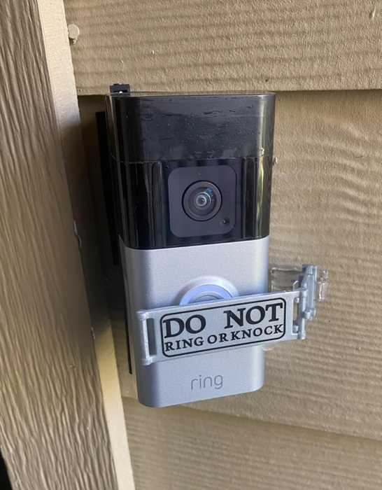 A doorbell camera with a sign that reads,