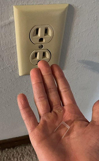 A reviewer holding the plastic adapter in their hand.