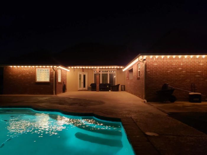 reviewer's photo of string lights hanging along the roofline at the back of a house near a pool patio area