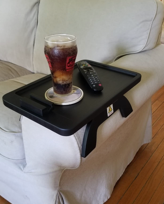 A reviewer's sofa tray table rests comfortably on the arm of the couch, with a drink and remote sitting on top for easy access.