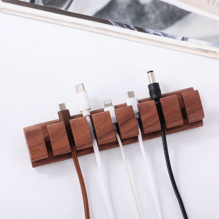 A dark wood cord organizer holding cords in a well-ordered fashion.