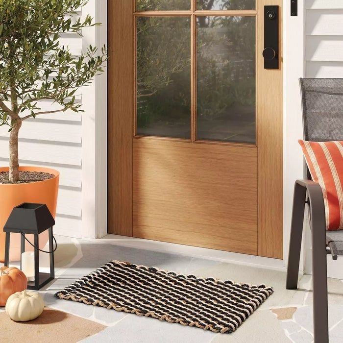 A front door featuring a welcome mat, a potted plant, and a chair adorned with a striped cushion