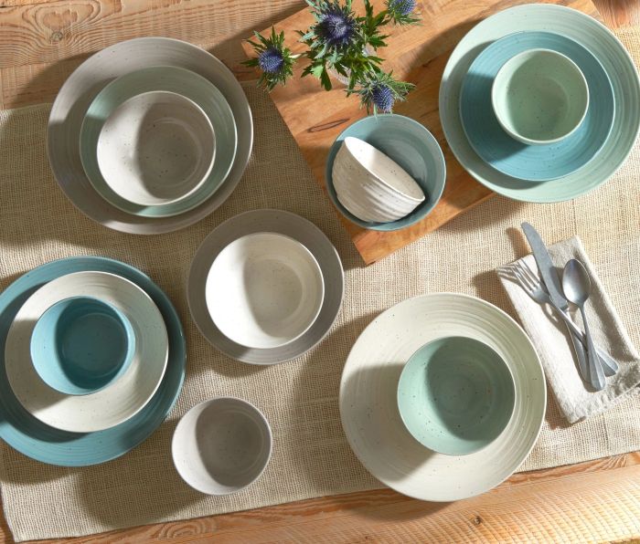 A top-down view of a beautifully arranged multicolored dinnerware set, elegantly displayed on a dining table.