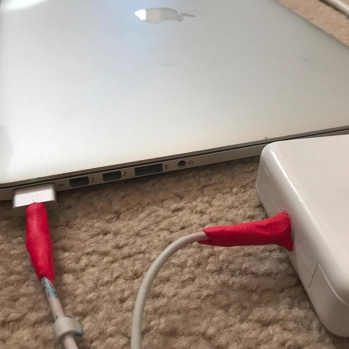 A red Sugru reinforcement on Mac charger cables where the wires meet the MagSafe plug and the power brick.