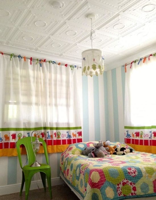 A child’s bedroom with a patterned bedspread, plush toys on the bed, and vibrant, animal-themed curtains
