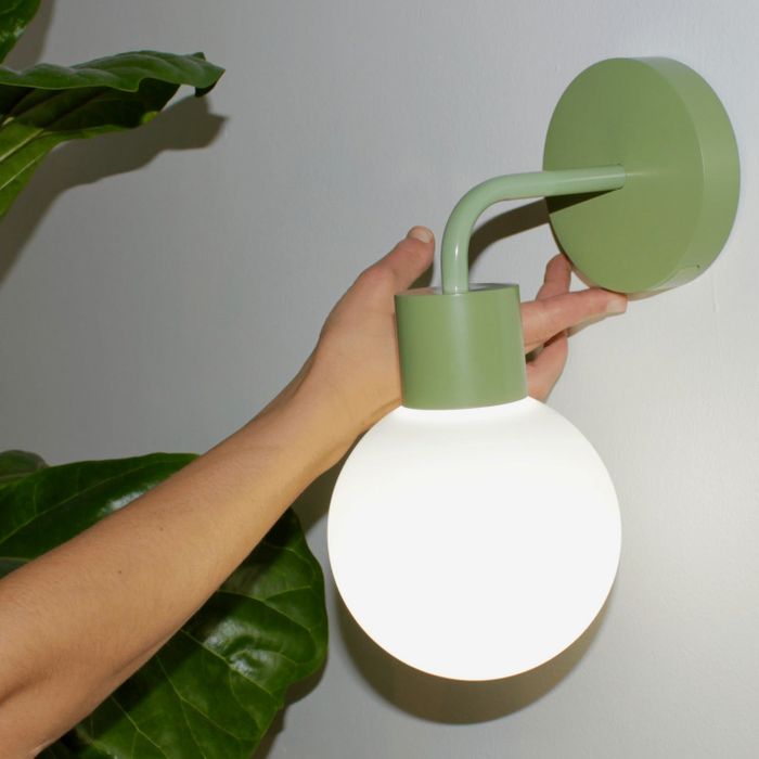 The sage green poplight mounted on a white wall.