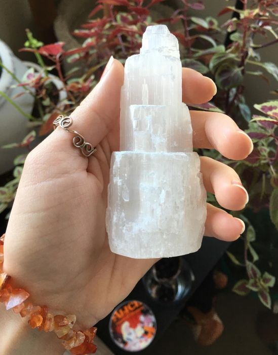 A reviewer showcasing the beautiful Selenite crystal in their hand, highlighting its sleek and luminous design.