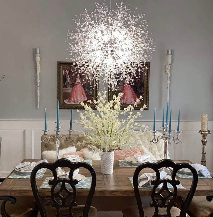 A dining room illuminated by the cool glow of the chandelier hanging above the table