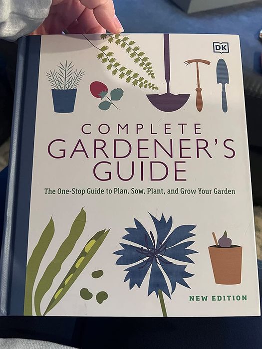 A reviewer displays the cover of Simon Akeroyd's comprehensive gardening guide