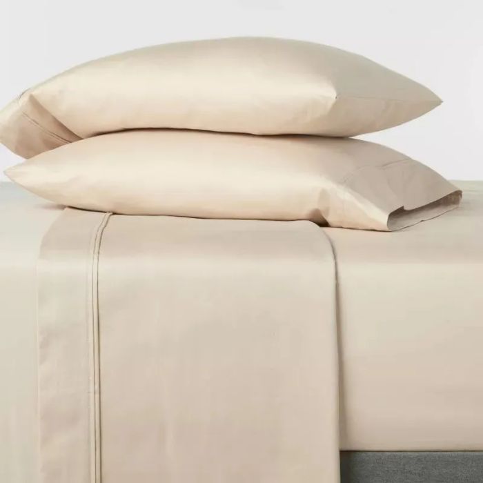 Two satin pillows stacked on a coordinating sheet set, presenting a luxurious bedding choice