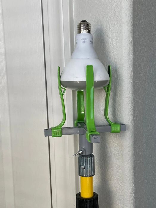 An LED bulb installed on a gray and green adjustable lamp holder connected to a yellow pole.