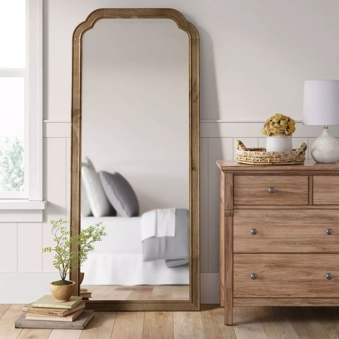 The full-length mirror placed against the wall in a cozy bedroom setting