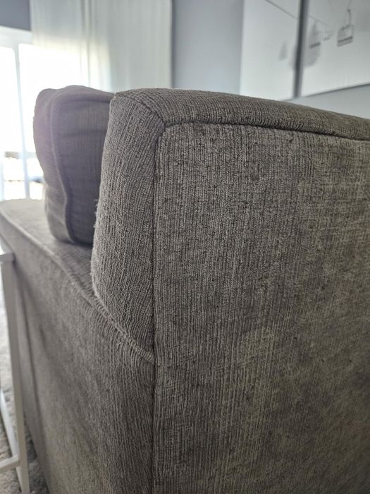 A close-up of a sofa corner, highlighting its textured fabric and cushioned backrest in a contemporary living room.