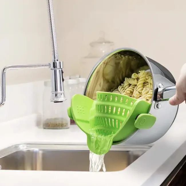 A model using a green snap-on strainer to drain pasta from the pot.