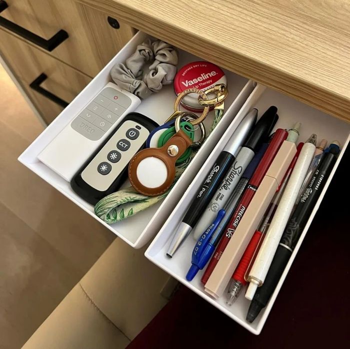 A reviewer shows two white drawers, filled with pens, keys, and other office supplies, installed neatly under their desk.