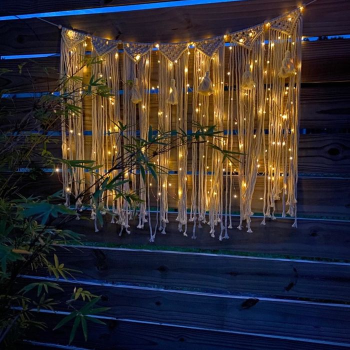 A reviewer’s macramé wall art adorned with delicate string lights, adding a cozy, illuminated touch.