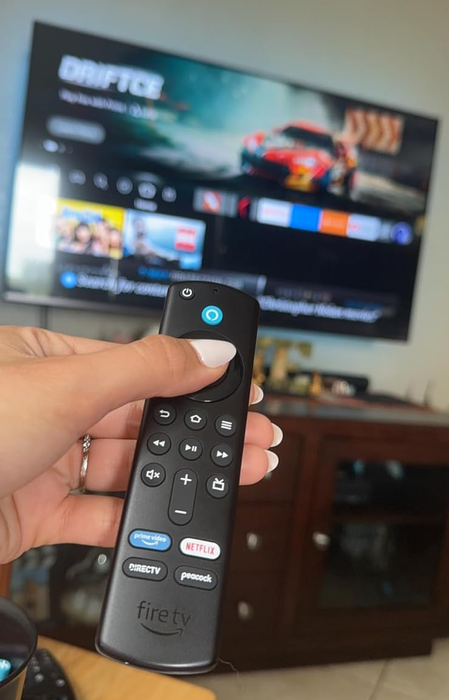 A reviewer holding the Amazon Fire TV Stick in hand, ready to plug it in.