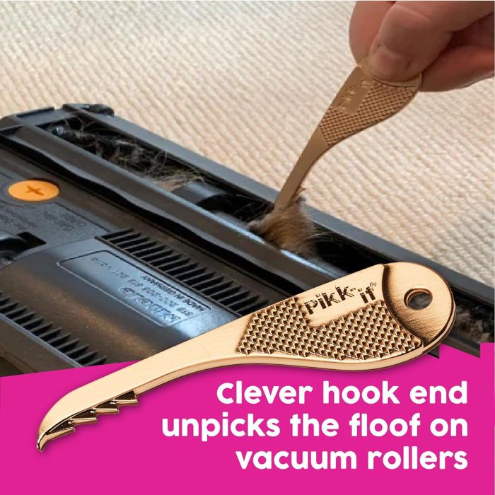 A hand using a tool to remove hair from a vacuum cleaner's roller, perfect for maintenance.