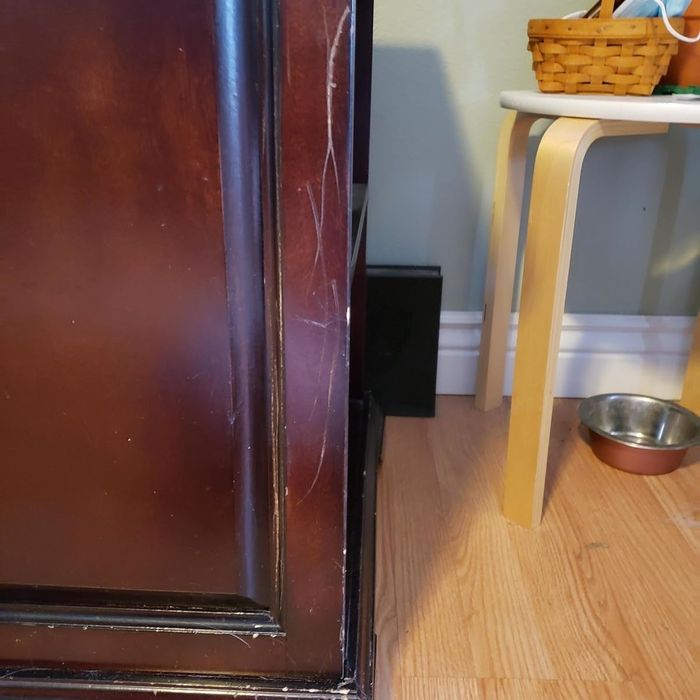 A before image of a scratched piece of wooden furniture in need of repair.