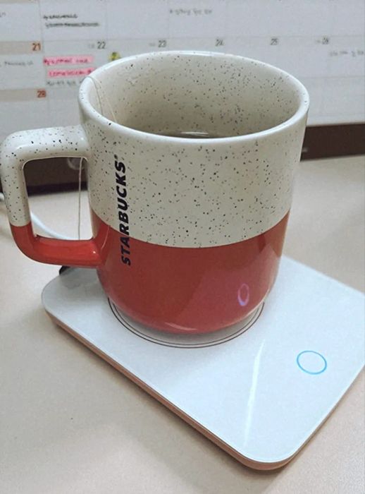 A mug sitting on a sleek, minimalist square white mug warmer.