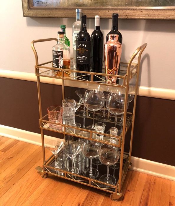A gold bar cart adorned with glasses