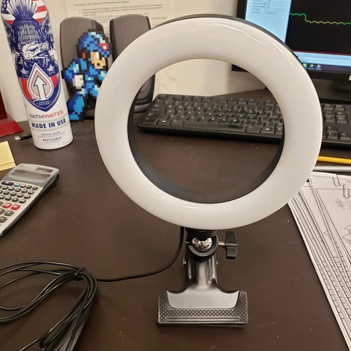 A reviewer's photo showing an unlit ring light with an attached clamp resting on a desk.