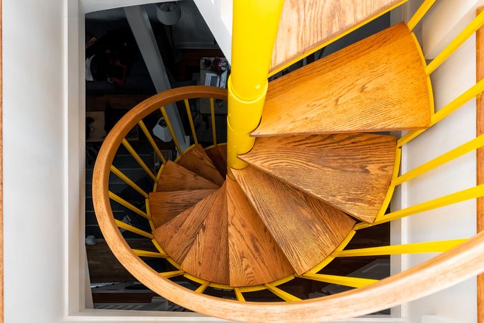 Spiral staircase with wooden steps and a yellow central pole, viewed from above