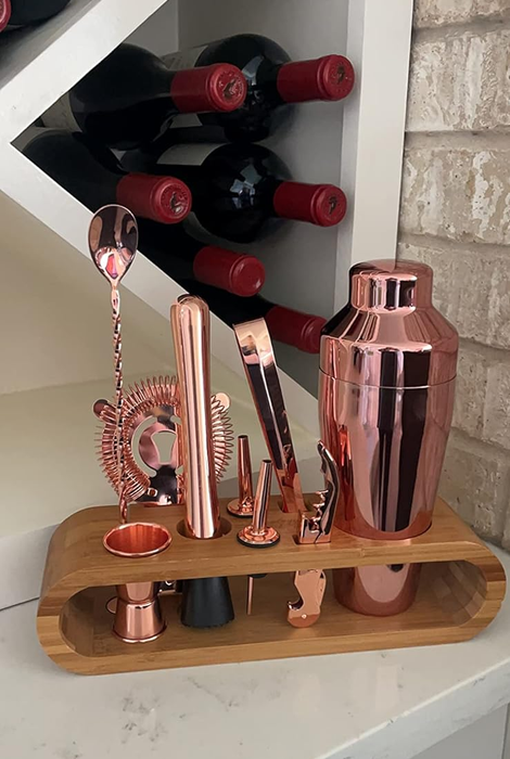 Copper mixology tools displayed in a wooden stand