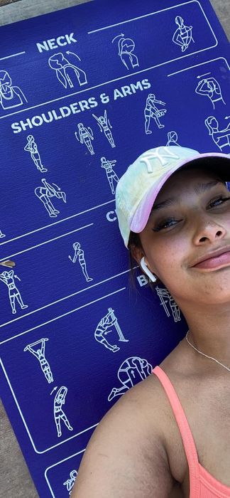 A reviewer in a tank top and cap smiles beside a guide for neck, shoulders, arms, core, and back stretches.
