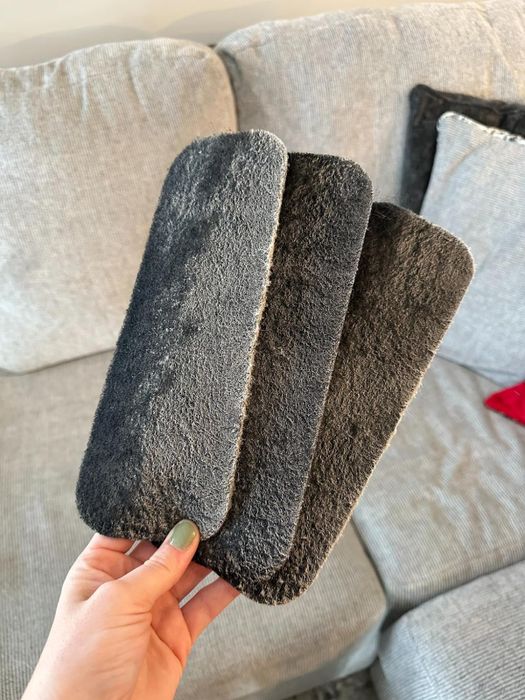 A person holding three used carbon filters, all covered in dust.