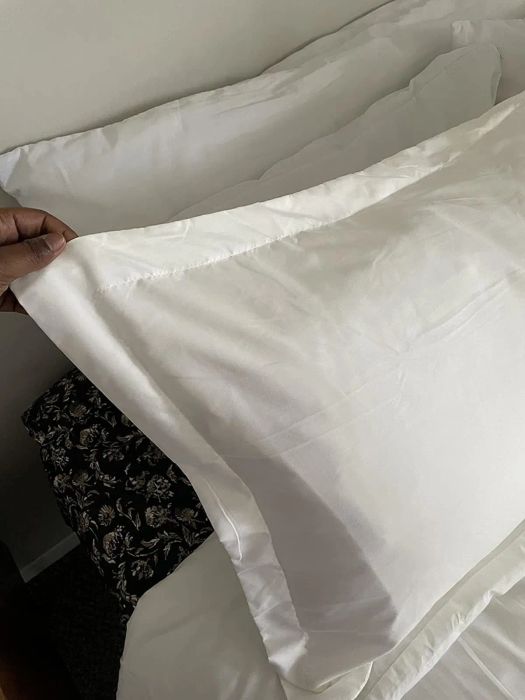 A person holding a corner of a simple duvet cover, displaying the texture and quality of the material
