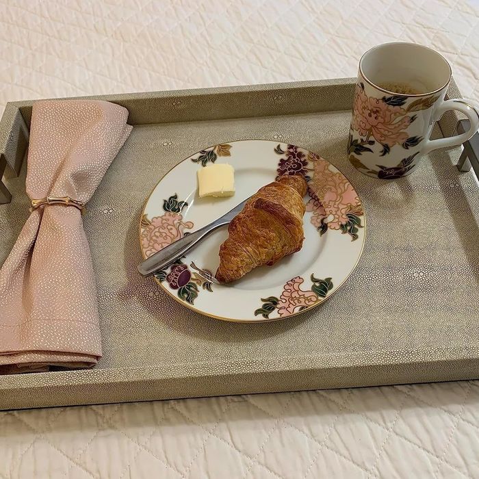 A reviewer's decorative setup featuring a plate with a croissant and butter, accompanied by a pink napkin.