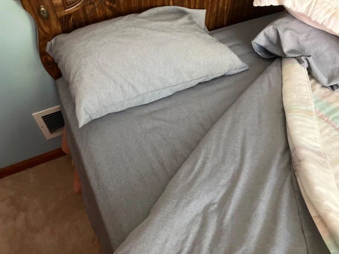 A disheveled bed with a pillow and wrinkled sheets