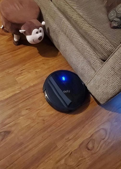 The black robot vacuum on the floor.