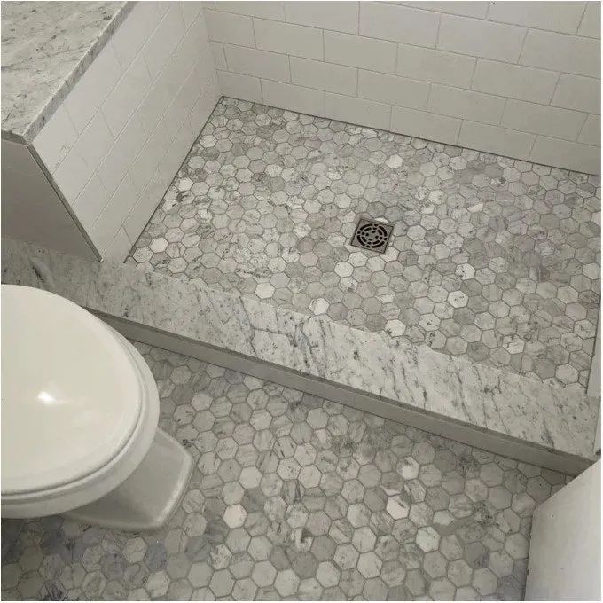 A reviewer’s snapshot showcasing the stunning marble tile installed on both a bathroom floor and a shower floor, adding a luxurious aesthetic.