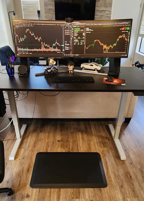 Another reviewer’s anti-fatigue mat sits in front of a standing desk equipped with two monitors.