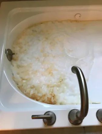 A reviewer's photo showing a jacuzzi-style tub filled with dirty foam.