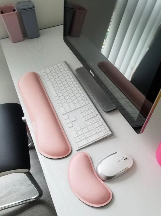 A reviewer's pink keyboard and mouse wrist rests placed on their computer desk.