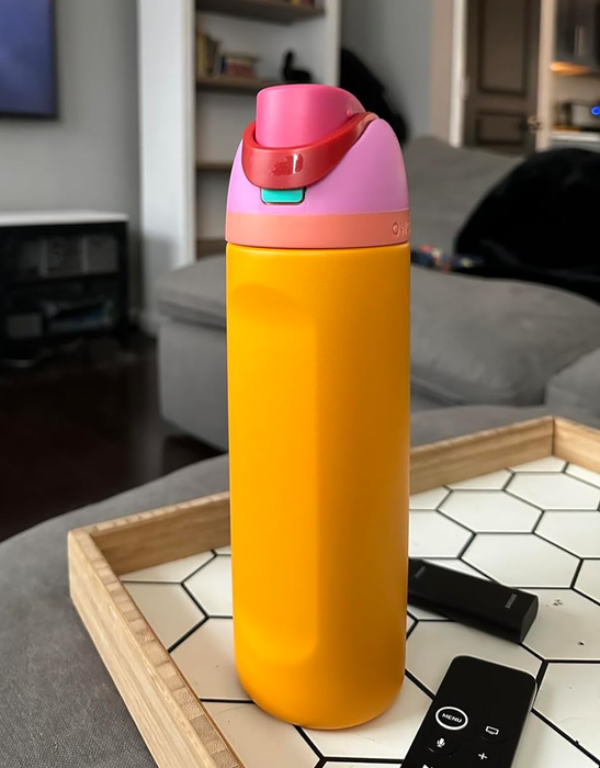 A vibrant orange Owala tumbler with a pink lid, ready to keep your beverage cold.