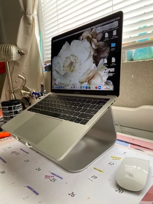 A reviewer's photo showing a silver laptop stand on a desk with a laptop raised on it.