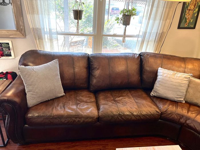 The same brown leather sectional sofa now with firmer, more supportive cushions and pillows.