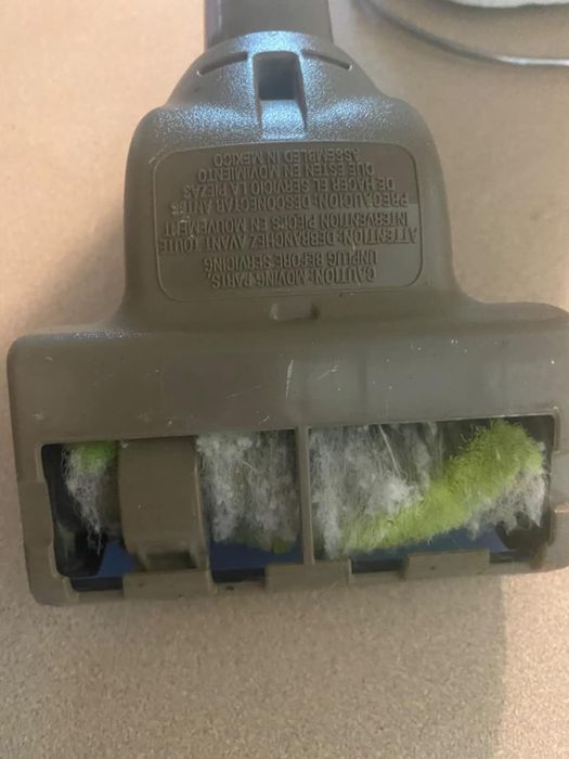 A vacuum cleaner head covered in accumulated dust and fibers.