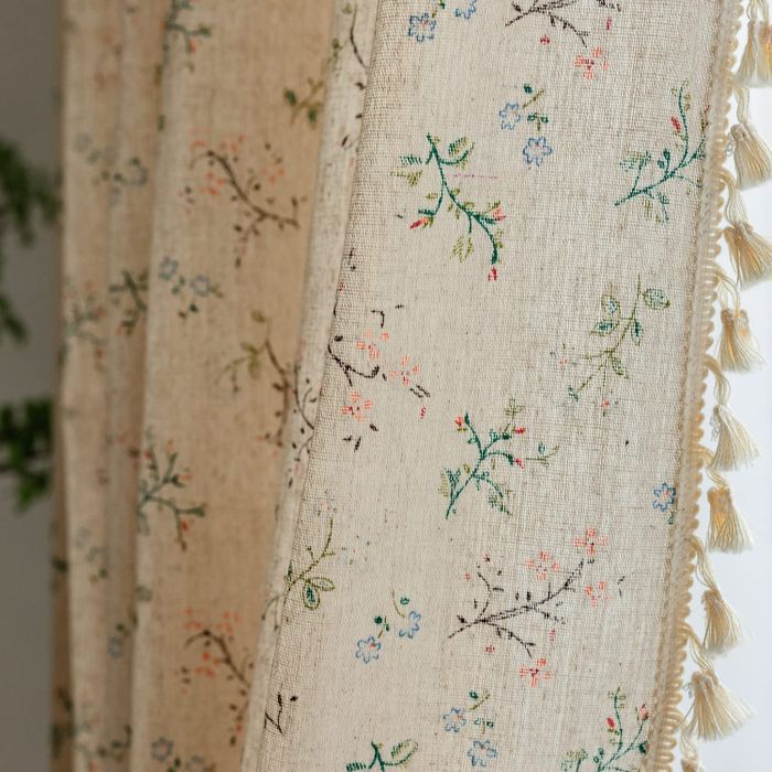 Floral curtains featuring tassels along the edges.