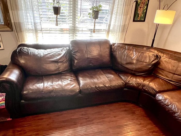 A sagging brown leather sectional sofa in a cozy living room setting.