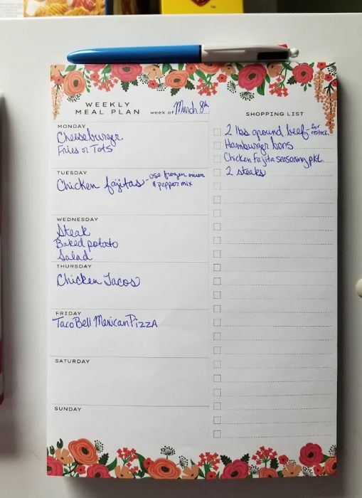 A white pad with orange floral accents featuring a section for planning meals for each day of the week on one side, and a blank grocery list on the other.